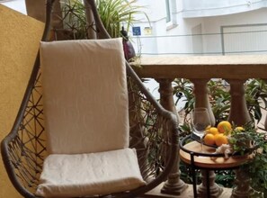 A wicker chair with a cushion, a small round table with a fruit bowl, and a glass of water. - Cozy Vodice Garden Apartments With Terrace and BBQ (Vodice)