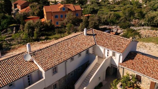 A coastal residential area with terracotta-tiled buildings, a clear view of the sea, and a hilly landscape. - Vitality Island Citadela Apartments (Mali Losinj)