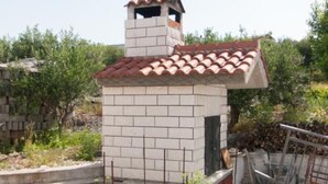 A small brick structure with a tiled roof, surrounded by vegetation. - Apartments Ruzarija (Marina)