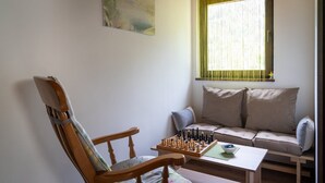 A cozy room with a wooden chair, a sofa, and a chessboard on a small table.