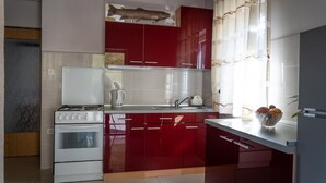 A modern kitchen with red cabinets, a white stove, and a sink.
