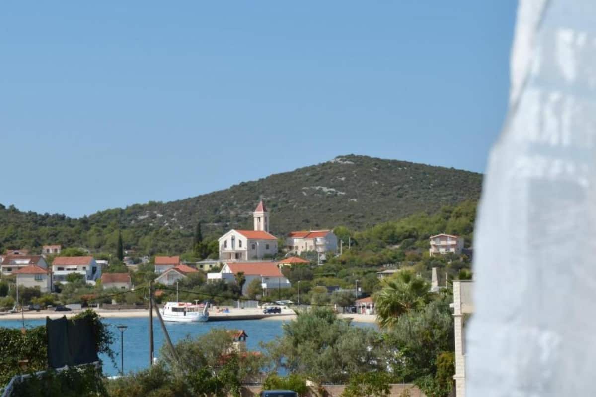 A coastal village with a prominent church, a beach, and a hill in the background.