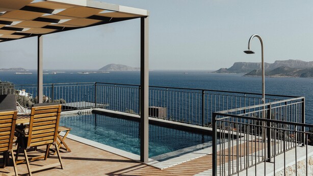 Zwembadterras met uitzicht op zee, een pergola en een tafel met stoelen.