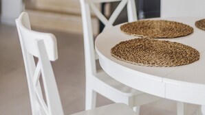 Een eethoek met een witte tafel en stoelen, voorzien van geweven placemats.