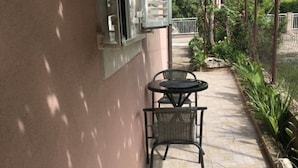 A patio with two tables and chairs, a tiled floor, and a fence enclosing a garden area. - Stefanija Residence Umag (Umag)