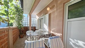 A balcony with a table and chairs, a potted plant, and a view of the sea. - Stefanija Residence Umag (Umag)