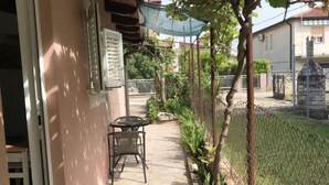 A patio with a table and chairs, a fence, and a stone structure in the background. - Stefanija Residence Umag (Umag)