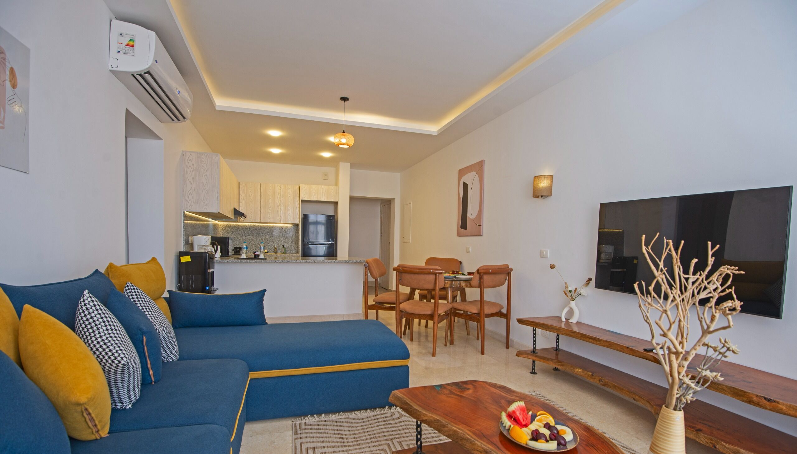 Una sala de estar moderna con un sofá azul, una mesa de centro de madera y un televisor.