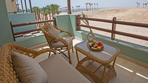 A balcony with wicker furniture, a table with fruit, and a view of the beach. - Spacious Two bedroom in Azzurra with Terrace Sahl Hasheesh (Sahl)