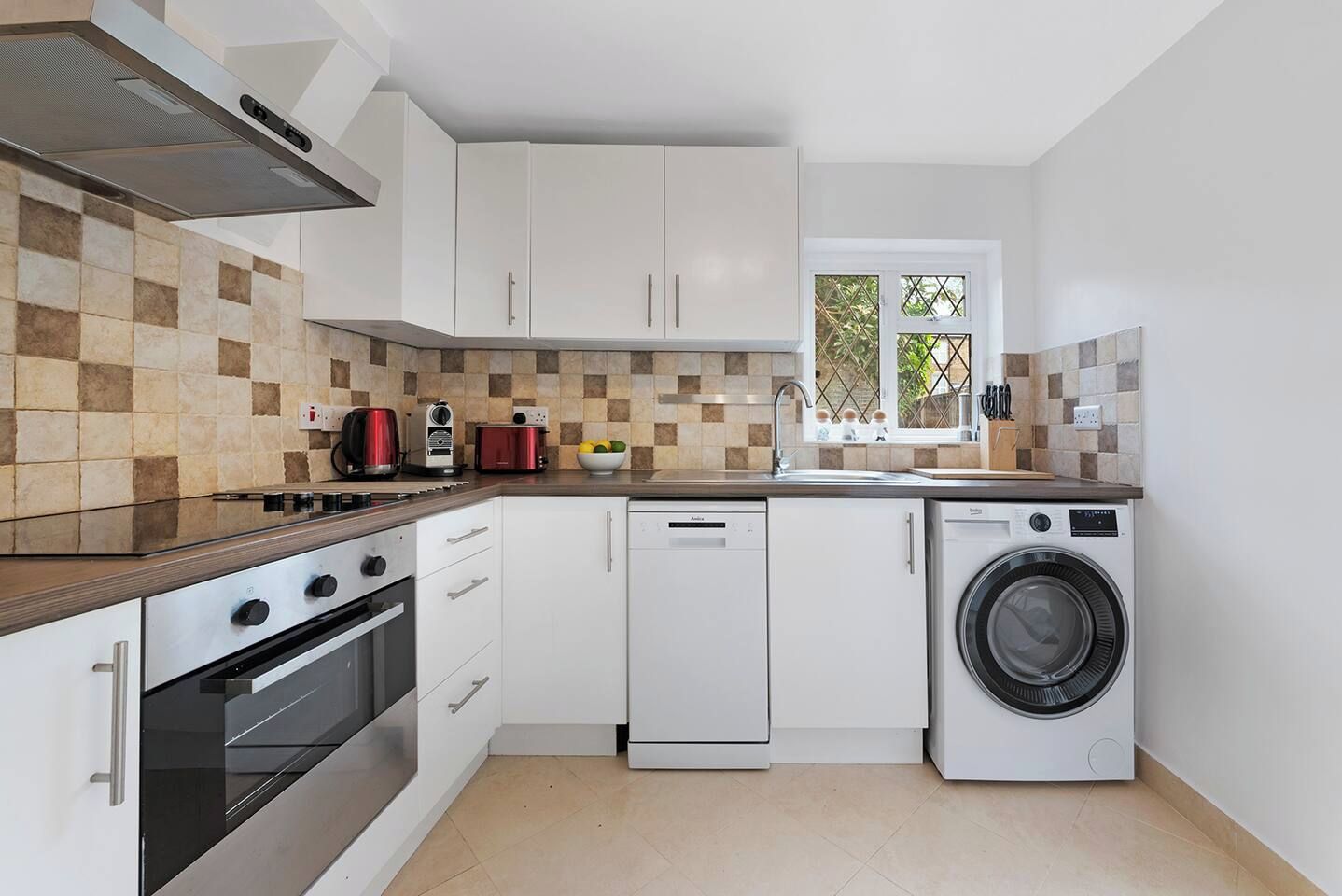 A compact kitchen with a gas stove, a dishwasher, and a washing machine.