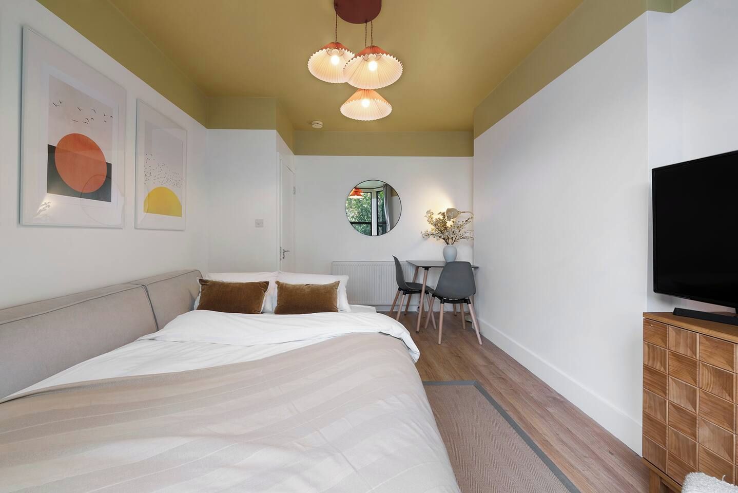 A modern bedroom with a large bed, a desk, and a television.