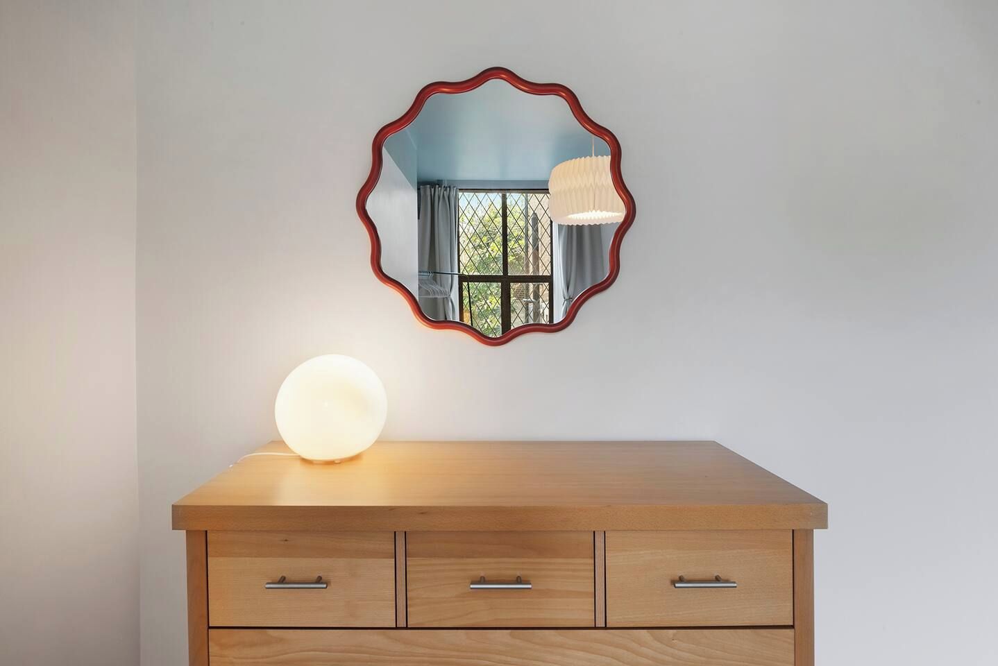 A wooden dresser with three drawers and a round light on top.