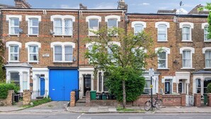 A row of terraced houses with a blue door, a bicycle, and a tree in the foreground. - Evershot Rd N4, Crouch Hill, Finsbury Park (London)