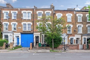 A row of terraced houses with a blue door, a bicycle, and a tree in the foreground.