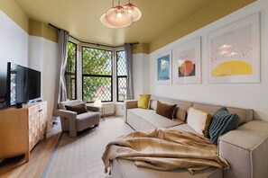 A modern living room with a sofa, armchair, and a television on a wooden cabinet.