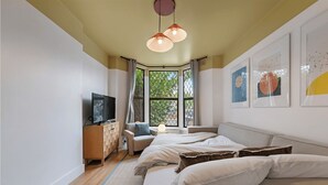 Una camera da letto moderna con un grande letto, una televisione su un mobile in legno e opere d'arte alle pareti.