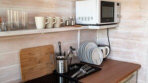 A kitchen with a microwave, a coffee maker, and various utensils on the counter.