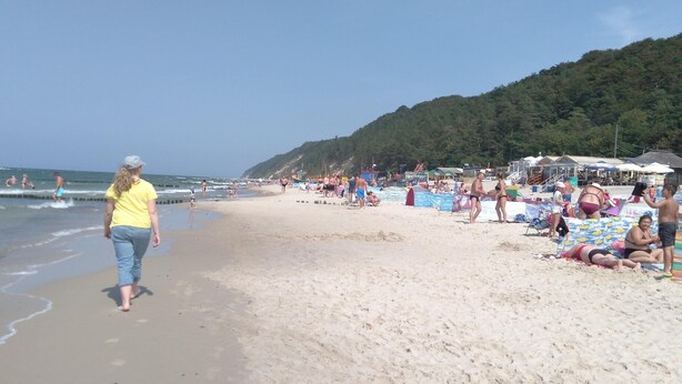 A beach with people sunbathing and swimming.