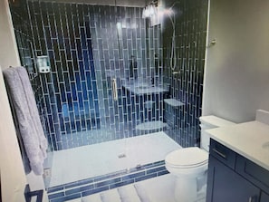 A bathroom with a tiled shower enclosure, a toilet, and a sink area. - Brand New Spacious 5-bedroom house in awesome Downtown Blue Ridge. (Blue Ridge)