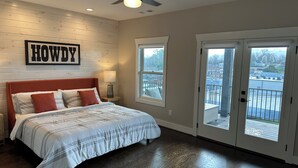 A bedroom with a bed, a ceiling fan, a window, and a door leading to a balcony.