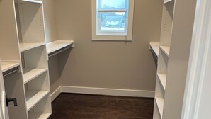 A walk-in closet with open shelves, a window, and a wooden floor.