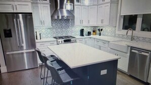 A modern kitchen with stainless steel appliances, a central island, and pendant lighting.