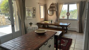 A kitchen with a tiled countertop, a wooden table, and a view of the outdoors.