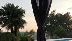 A bottle of champagne, glasses, and a meat cut on a tray by a poolside.