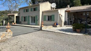 A two-story building with a tiled roof, green shutters, and a satellite dish.