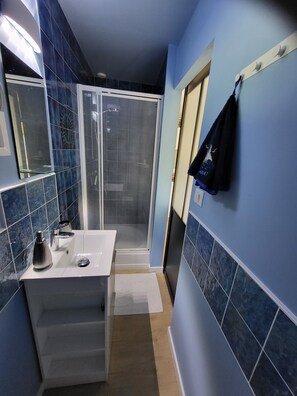 A bathroom with a shower, a sink, and a towel rack.