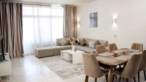 A modern living room with a sofa, coffee table, and dining table with chairs.