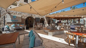An outdoor seating area with stone walls, wooden furniture, and a sign for La Rocca Restaurant & Lounge.