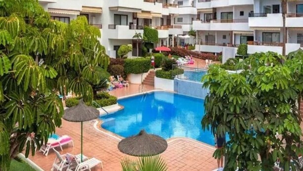 Un complexe hôtelier comprenant plusieurs bâtiments blancs, une piscine centrale et une végétation luxuriante.
