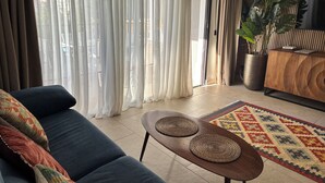 Un salon avec un canapé, une table basse, un tapis à motifs et une plante.