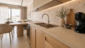 A modern kitchen with a large window, a dining area, and a coffee machine. - Exclusive Retreat off the Sea Front Promenade (Il-Gzira)