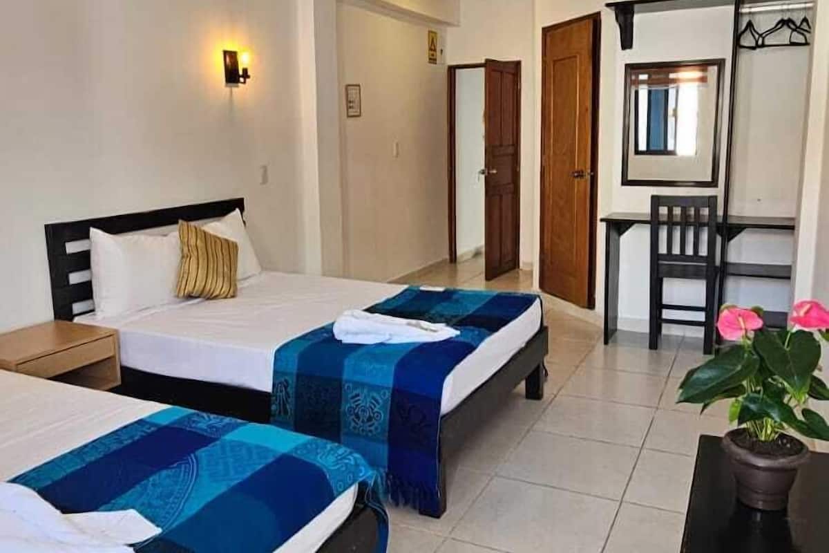 Een hotelkamer met twee bedden, een bureau en een stoel.