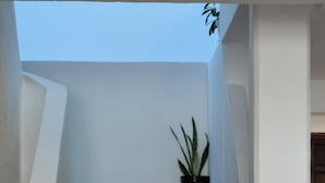 A staircase with a potted plant, leading to a room with a floral-patterned bedspread. - Calma Chicha Rooms (Playa del Carmen)