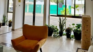 A lobby with a yellow chair, potted plants, and a sign indicating an exit. - Calma Chicha Rooms (Playa del Carmen)