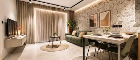 A modern living room with a dining area, a sofa, a TV, and a stone wall.
