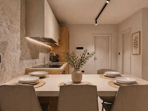 A modern kitchen with a central island, built-in appliances, and a dining area with a table set for four.
