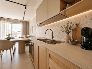 A modern kitchen with a large window, a dining area, and a coffee machine.