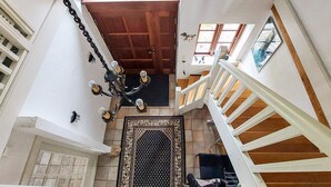 Una escalera con barandillas blancas y un candelabro con múltiples luces.