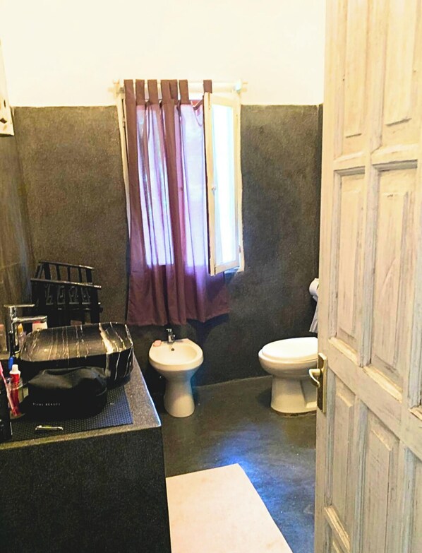 A bathroom with a bidet, toilet, and a sink with a black marble countertop. - Kisiwa Apartments Watamu at Ascot Resort  (Watamu)