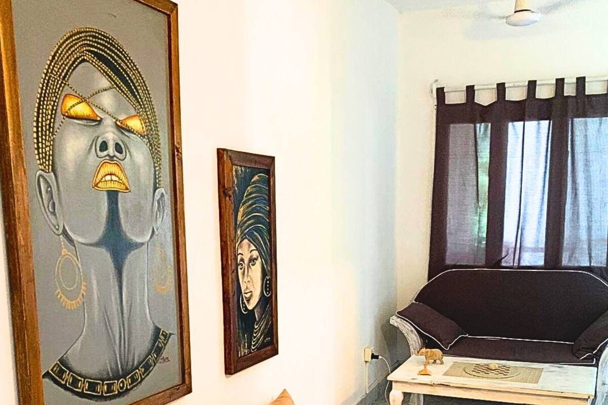 Un salon comprenant un canapé, une table basse, un tapis et deux œuvres d’art encadrées accrochées au mur.