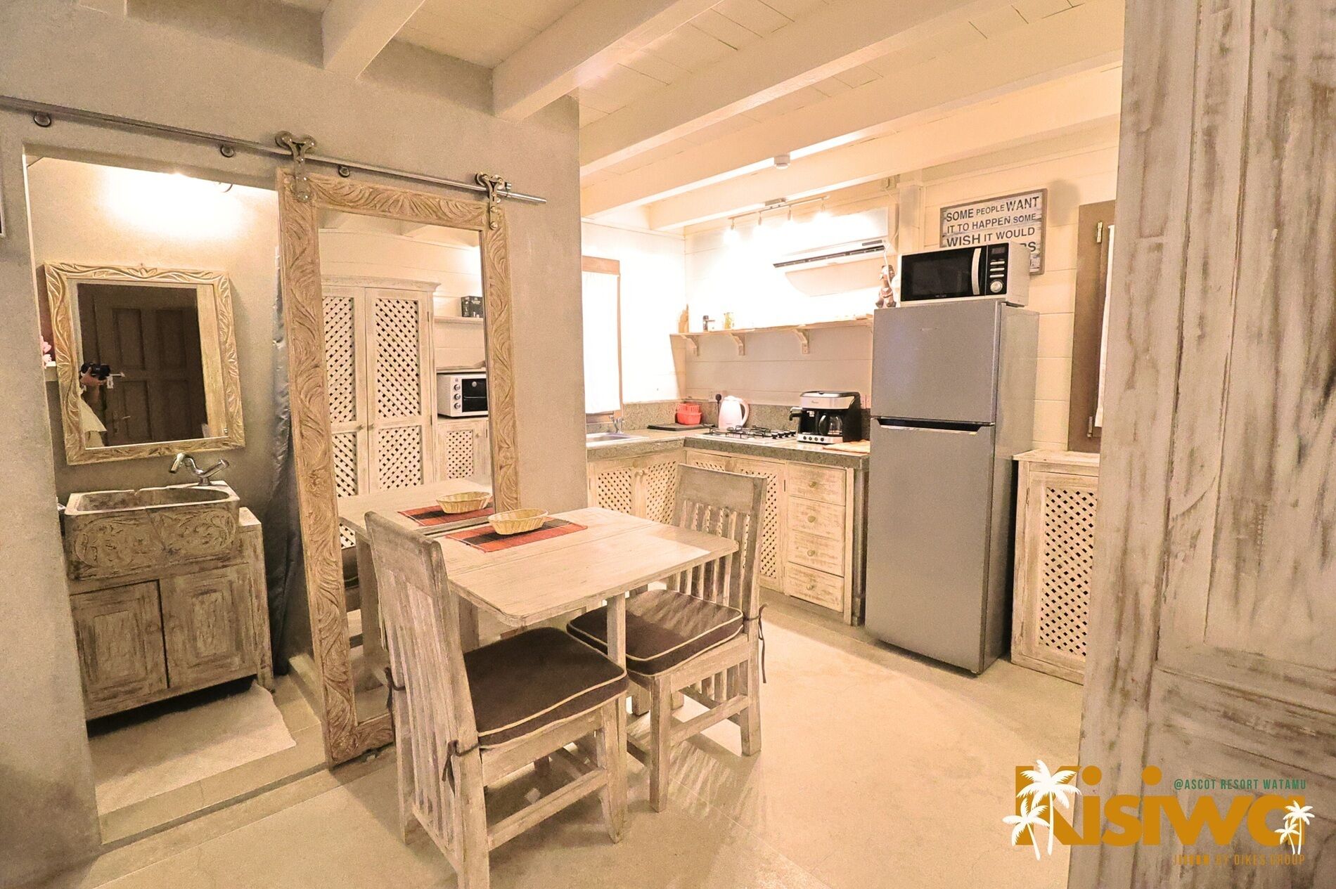 A compact kitchen with a dining table, a refrigerator, a microwave, and a sink.