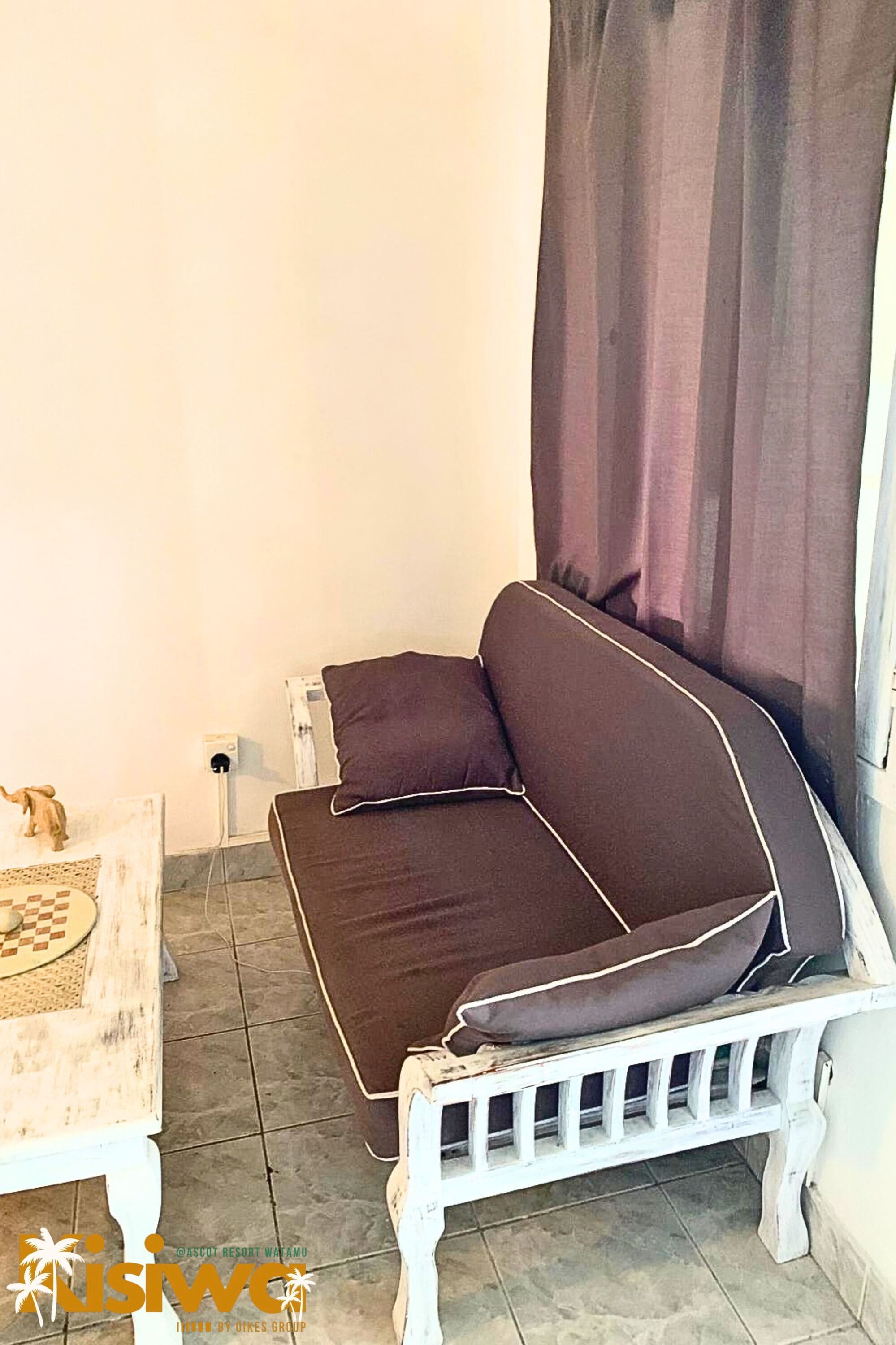 Un canapé blanc avec des coussins marron et un banc blanc adossé à un mur.
