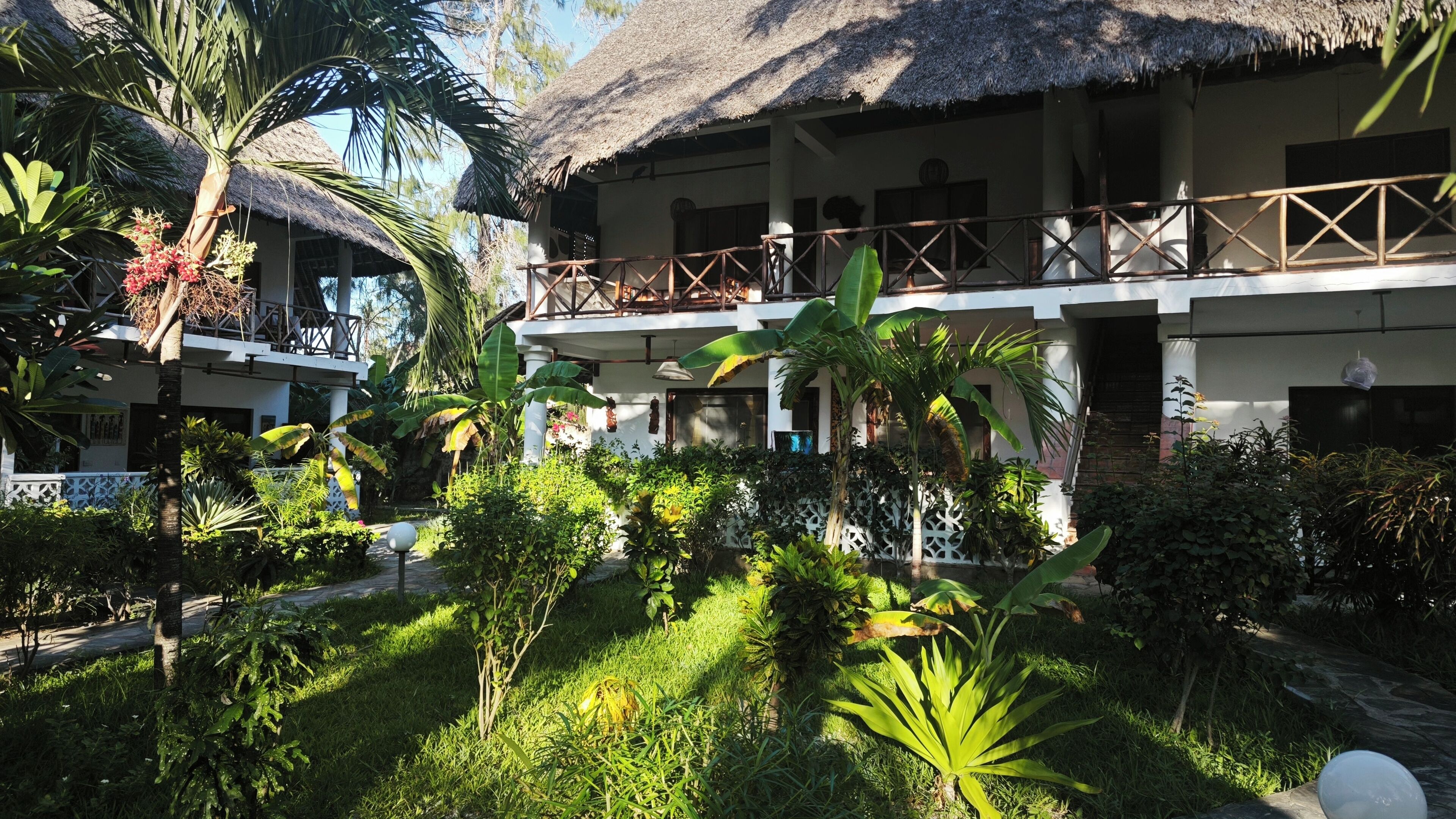 A resort with thatched-roof buildings, a covered outdoor area, and lush greenery.