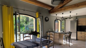 A modern kitchen with wooden cabinets, a stainless steel refrigerator, and a dining area with a table and chairs.