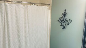A bathroom with a white toilet, a white shower curtain, and a green wall. - Charming 2-bedroom cottage with WiFi, AC in fabulous Elk Rapids (Elk Rapids)