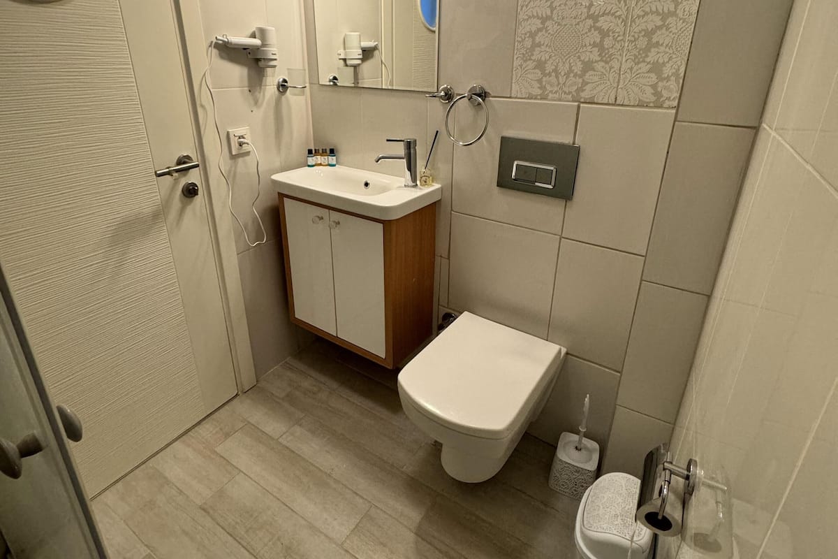 Un baño con inodoro, lavabo, espejo y zona de ducha.